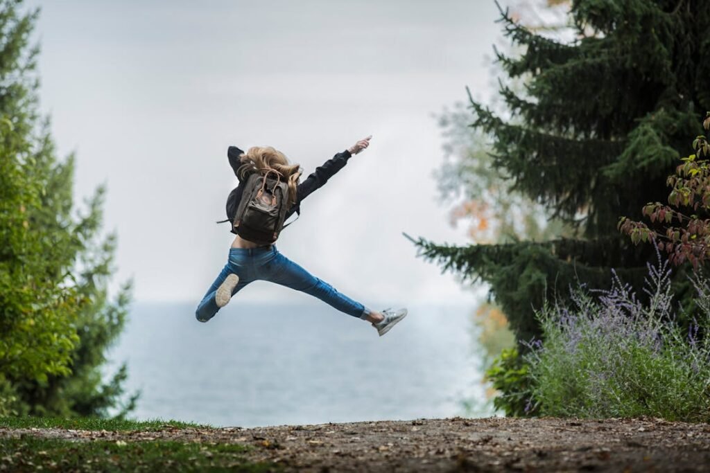 Woman jumps joyfully with backpack outdoors