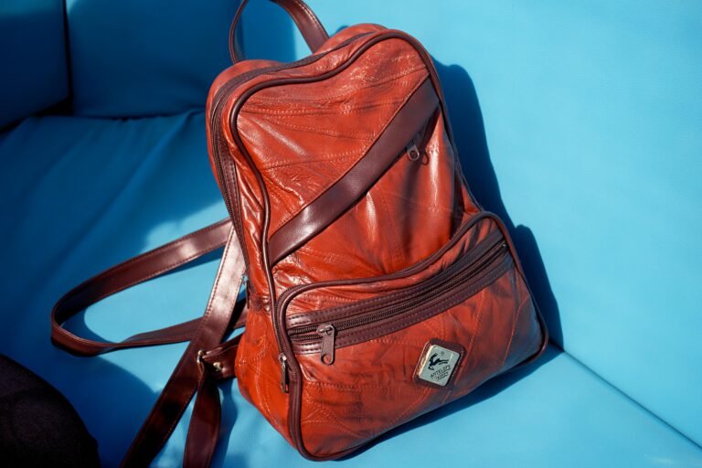 Brown leather backpack on blue seat.